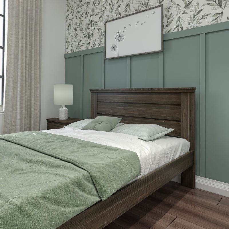 Modern bedroom interior featuring a dark wood bed frame, sage green bedding, paneled green accent wall with botanical wallpaper, wooden nightstand with white table lamp, neutral curtains and hardwood flooring