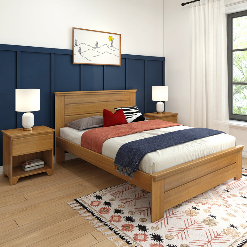 Modern bedroom with oak platform bed and matching nightstands, navy board-and-batten accent wall, white bedside lamps, patterned boho rug and layered neutral bedding