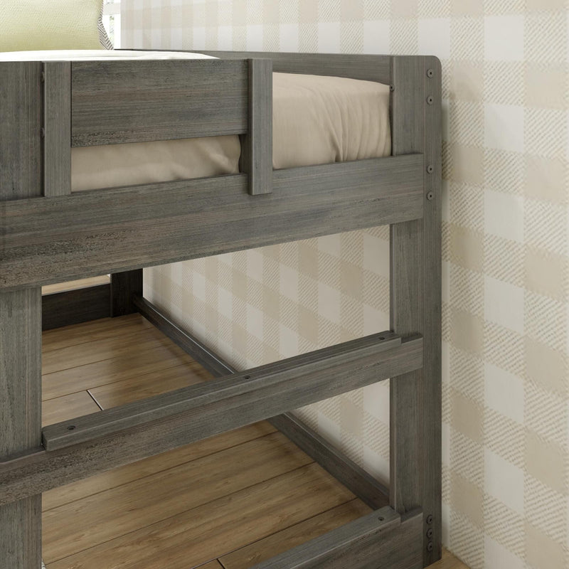 Weathered gray wooden bunk bed frame close-up with beige mattress and guardrail on hardwood floor against neutral plaid wallpaper