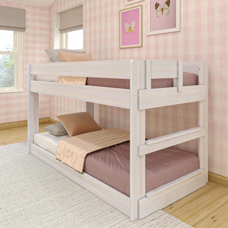 Whitewashed wooden twin bunk bed in a pink gingham girls’ bedroom with peach and brown bedding, ladder and framed butterfly wall art