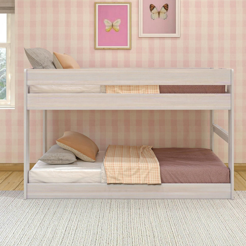 Twin bunk bed with white wood frame, peach and grey pillows, gingham throw, and pink plaid wallpaper with butterfly wall art in a cozy kids bedroom