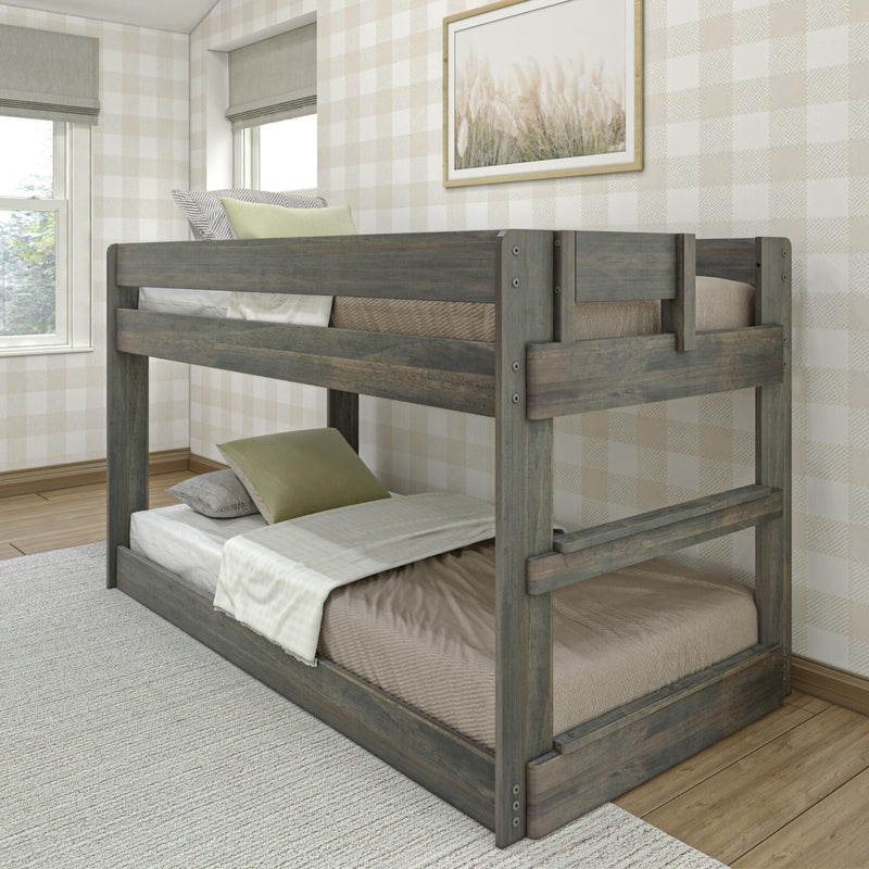 Rustic gray wooden twin-over-twin bunk bed in a neutral farmhouse bedroom with buffalo-check wallpaper, linen bedding, green accent pillows, framed coastal grass art and natural light from windows