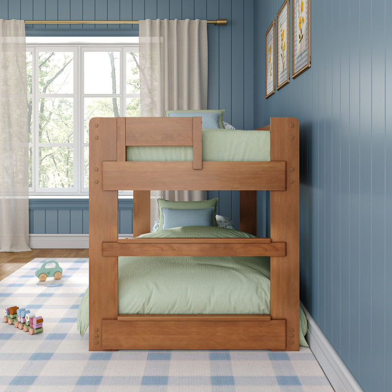 Wooden bunk bed in a blue paneled kids’ bedroom with green bedding, plaid rug, wooden toy train and sunlight streaming through sheer window curtains