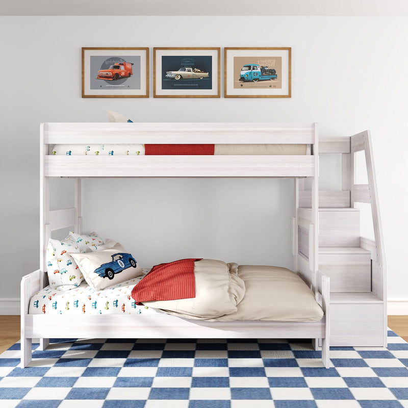 Light wood kids bunk bed with stairs, car-themed bedding and pillows, framed vintage car prints above, and blue checkered rug in a modern children's bedroom