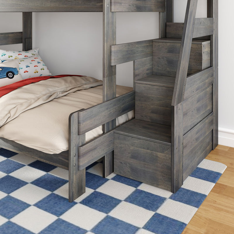 Gray wooden children's bunk bed with built-in staircase storage, beige bedding and car-print pillow on blue checkered rug