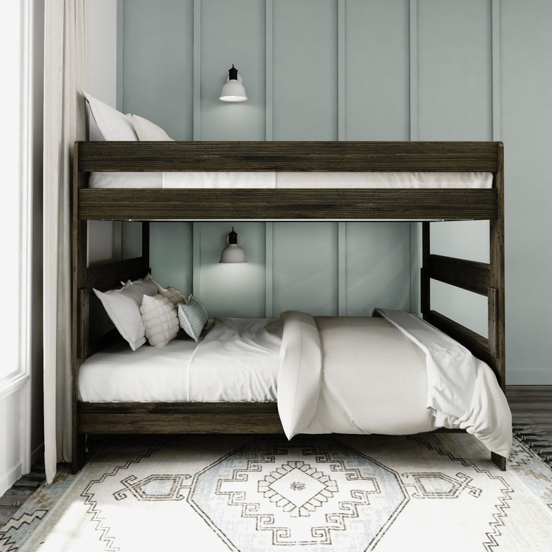 Dark wood bunk bed with white linens and pillows, wall sconces and pale blue paneled wall over patterned rug in modern bedroom