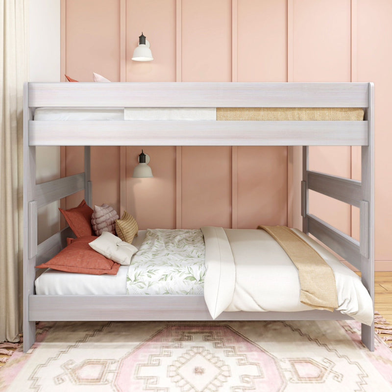Whitewashed wooden bunk bed with cozy floral bedding, coral pillows and pink paneled accent wall in a styled kids' bedroom