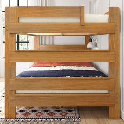 Wooden bunk bed with a colorful striped comforter in a bright bedroom setting.