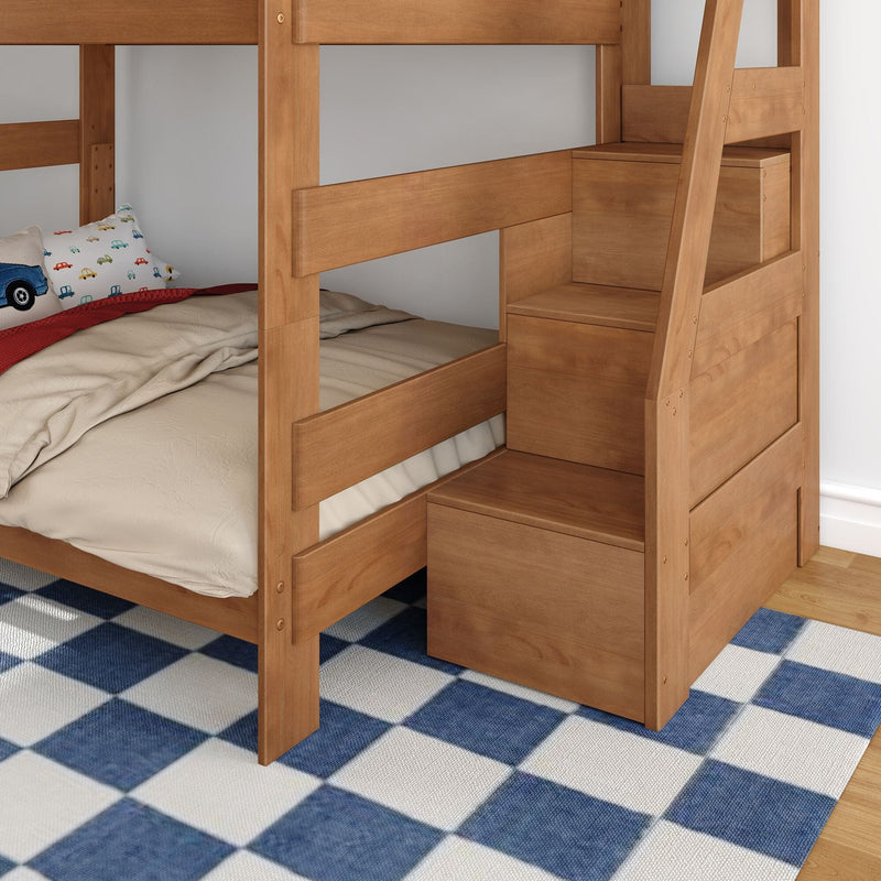Solid wood twin-over-twin bunk bed with built-in staircase drawers, natural finish, beige bedding and car-print pillow on blue plaid rug