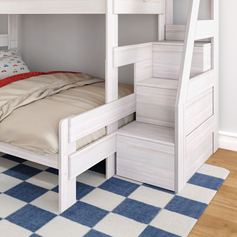 White wooden bunk bed with built-in storage staircase and drawers, lower twin bed with beige bedding and car-print pillow on blue checkered rug in a children's bedroom