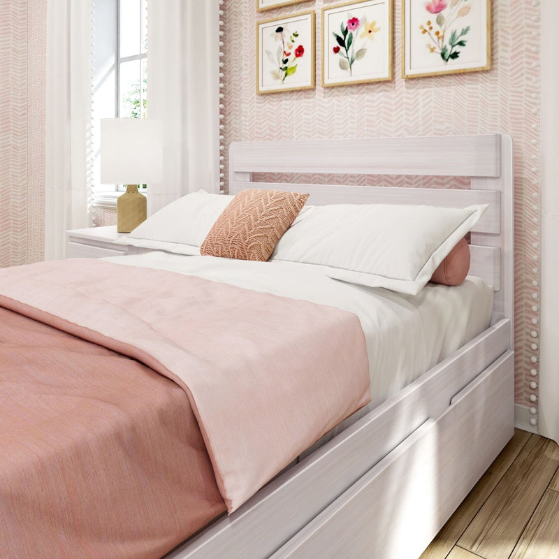 Blush pink bedroom with whitewashed wooden bed frame, soft pink duvet and pillows, knitted accent pillow, gold bedside lamp and framed floral artwork