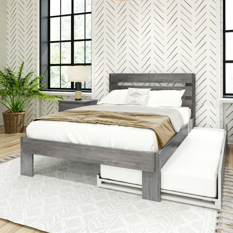 Modern farmhouse bedroom with gray wood platform bed, white linens and tan throw, geometric herringbone wallpaper, black grid windows, nightstand lamp and potted fern