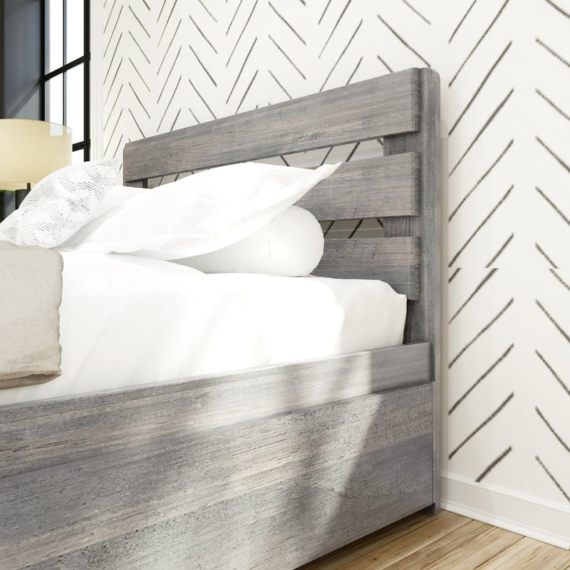 Close-up of modern gray wood bed frame headboard with white bedding, chevron wallpaper accent, bedside lamp and hardwood floor