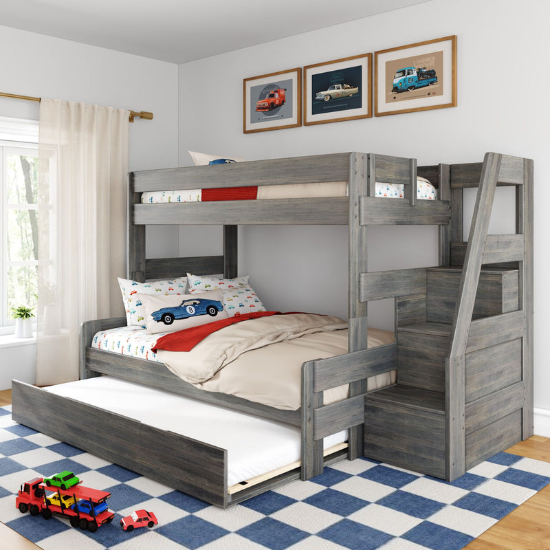 Gray wooden bunk bed with pull-out trundle in children's bedroom, car-themed bedding and pillows, framed vintage car prints, blue checkered rug and toy cars on floor.
