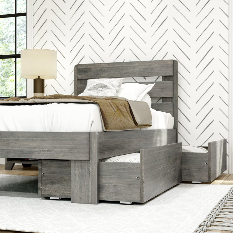Modern gray wood platform bed with built-in under-bed storage drawers open, white bedding and beige throw, bedside lamp and chevron wallpaper in a contemporary farmhouse bedroom