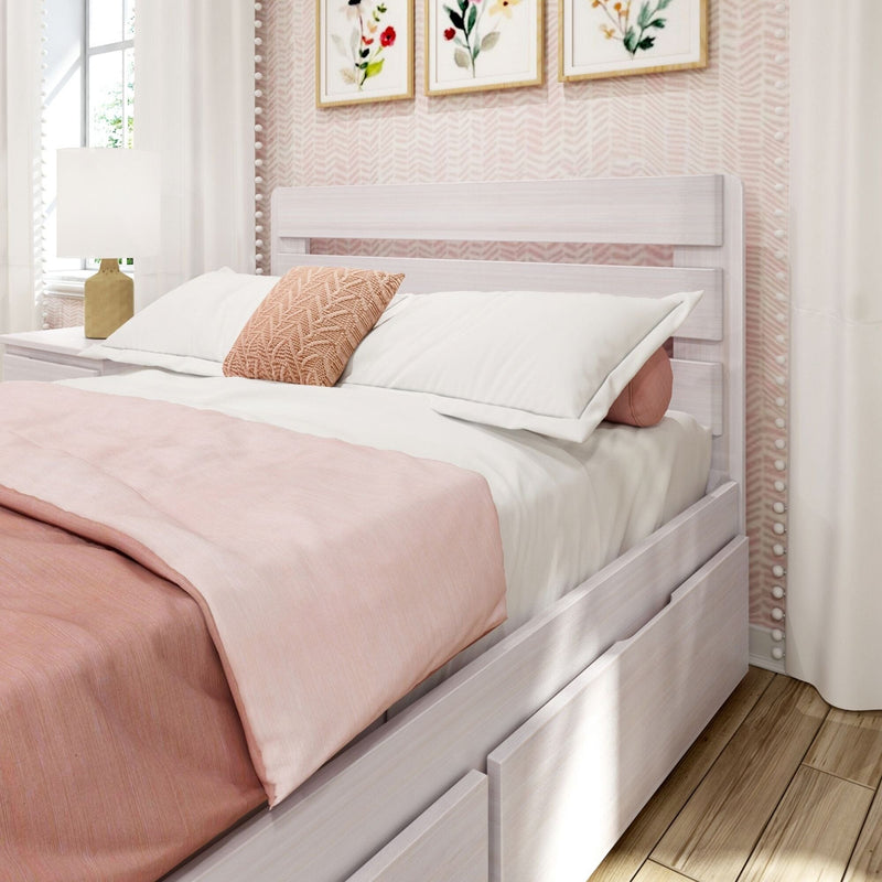 Blush pink bedding and textured knit pillow on a white wooden storage bed with drawers, bedside lamp and framed floral wall art in a cozy modern farmhouse girl's bedroom