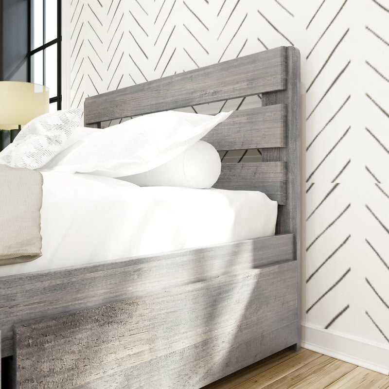 Close-up of a modern gray wood headboard with white bedding on a rustic platform bed in a Scandinavian bedroom featuring geometric chevron wallpaper and hardwood floors