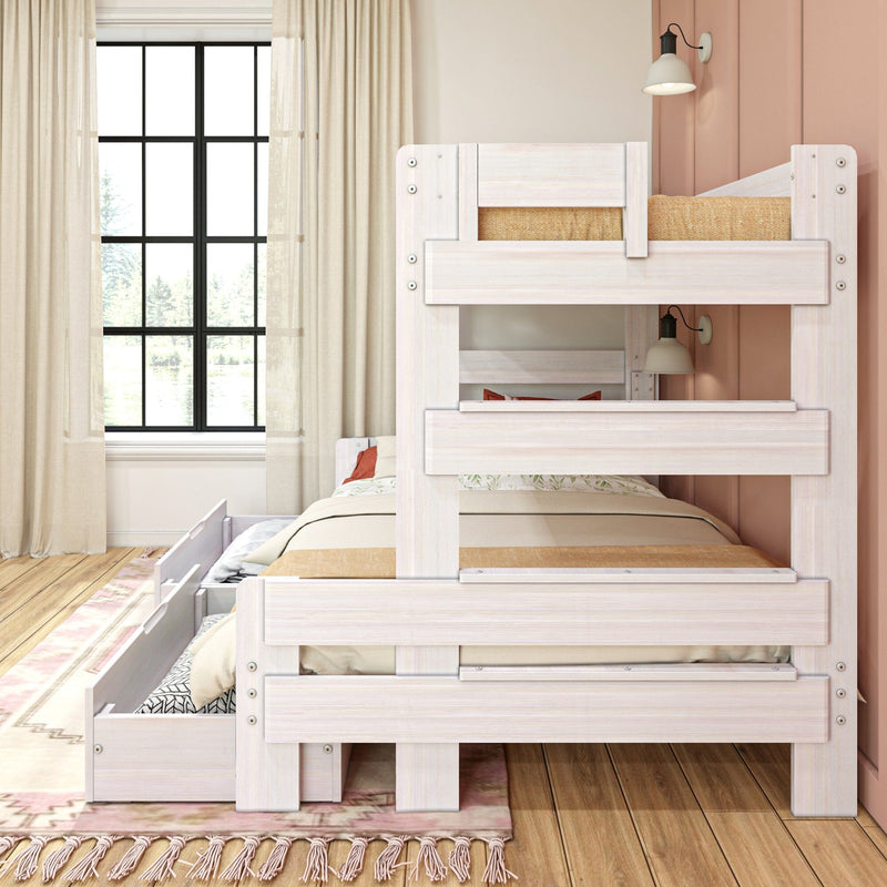 Whitewashed wooden bunk bed with pull-out trundle drawer in a bright kids' bedroom, hardwood floors, blush-pink accent wall, large black-framed window, neutral bedding and area rug