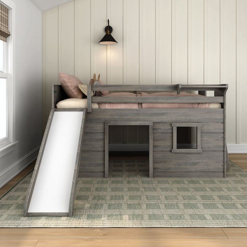 Rustic gray wooden kids loft bed with slide, pink bedding and stuffed bunny in a modern farmhouse kids' bedroom with paneled wall and wall sconce