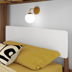Modern bedroom with mustard yellow bedding, wooden headboard, and elegant wall-mounted sconce.