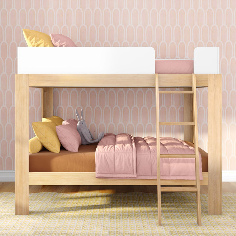 Wooden kids bunk bed with pink bedding, yellow throw pillows and plush bunny against pastel pink patterned wallpaper.