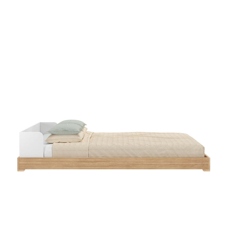 Wooden platform bed with beige bedding and green pillows, minimalist bedroom furniture.