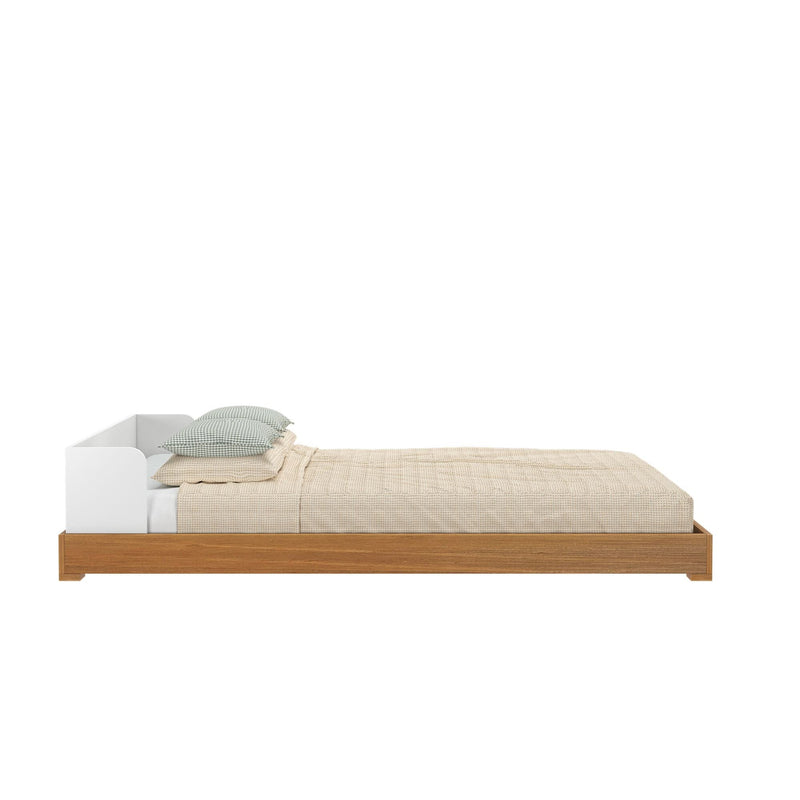 Minimalist wooden platform bed with beige bedding and green pillows, side view.