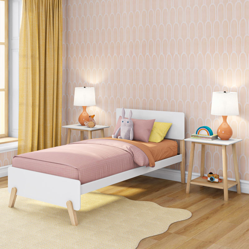 Pastel children's bedroom with pink twin bed, yellow curtains, peach geometric wallpaper, wooden nightstands with orange lamps and plush bunny toy