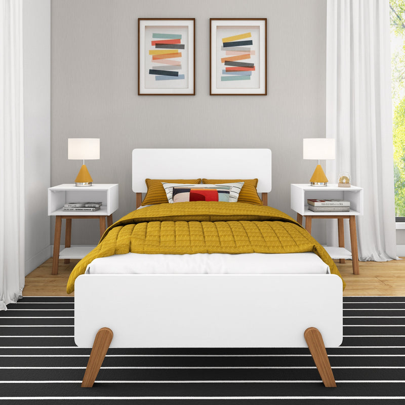 Modern minimalist bedroom interior with white bed frame, mustard quilted duvet and patterned pillow, mid-century bedside tables with yellow lamps, black-and-white striped rug, framed abstract wall art and neutral gray walls illuminated by natural light