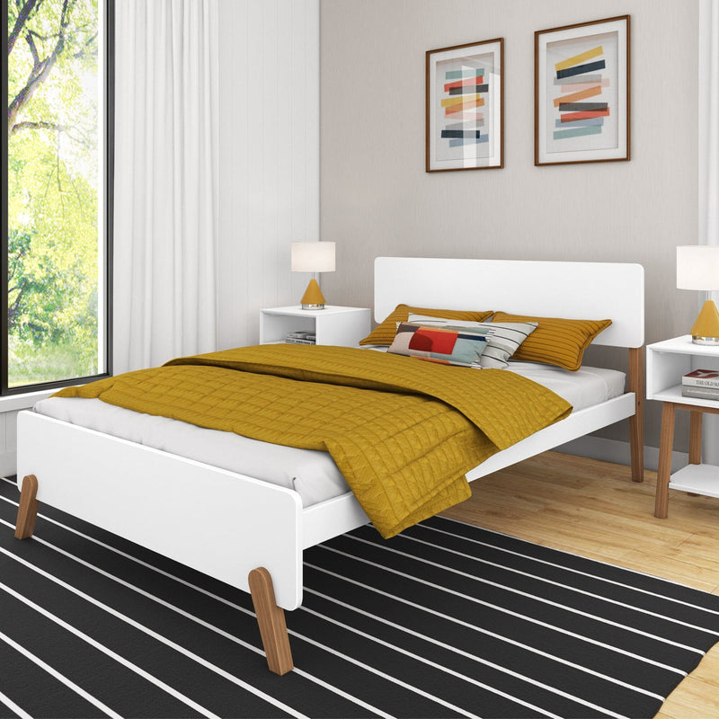 Modern bedroom with white platform bed, mustard yellow quilt and pillows, black striped rug, bedside tables, lamps and framed abstract wall art