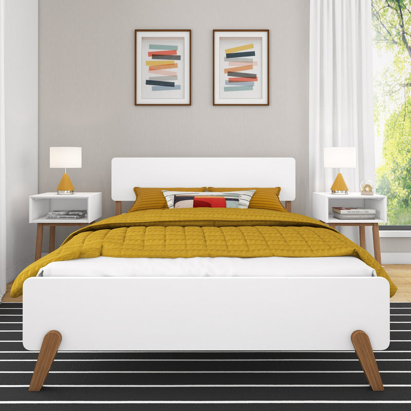 Modern Scandinavian bedroom with mustard yellow quilted bedding on a white mid-century platform bed, matching nightstands with yellow lamps and abstract framed wall art