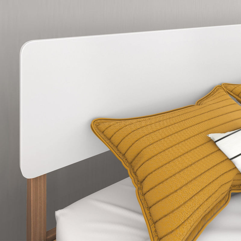 Modern bed with white headboard and mustard yellow pillows.