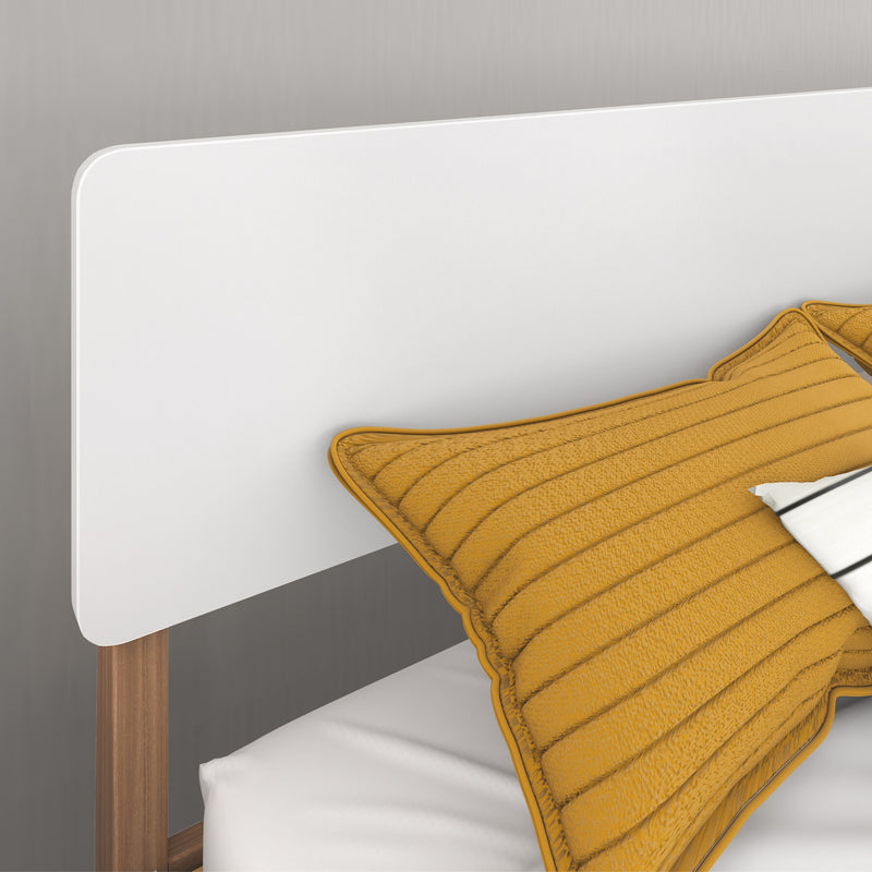 Close-up of modern white headboard with walnut wood bed frame and mustard yellow quilted pillow on white bedding in a minimalist bedroom design