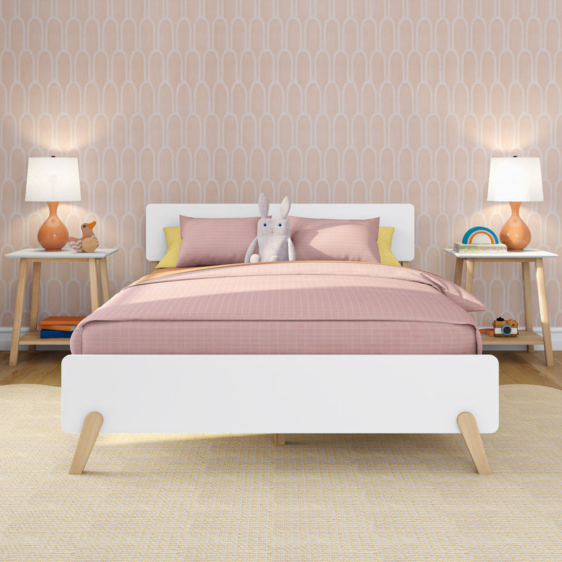 Modern kids' bedroom with pink bedding and stuffed bunny on a white bed, pastel arch-pattern wallpaper, wooden nightstands, orange bedside lamps and playful toys — nursery decor inspiration.