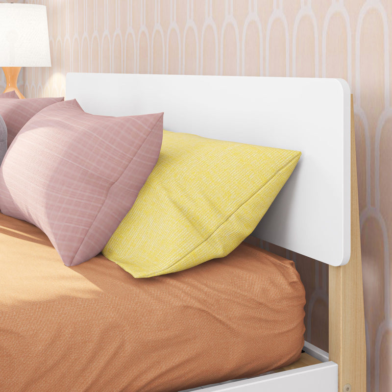 Modern bedroom interior with white headboard, pink and yellow pillows, orange bedding and bedside lamp against peach patterned wallpaper