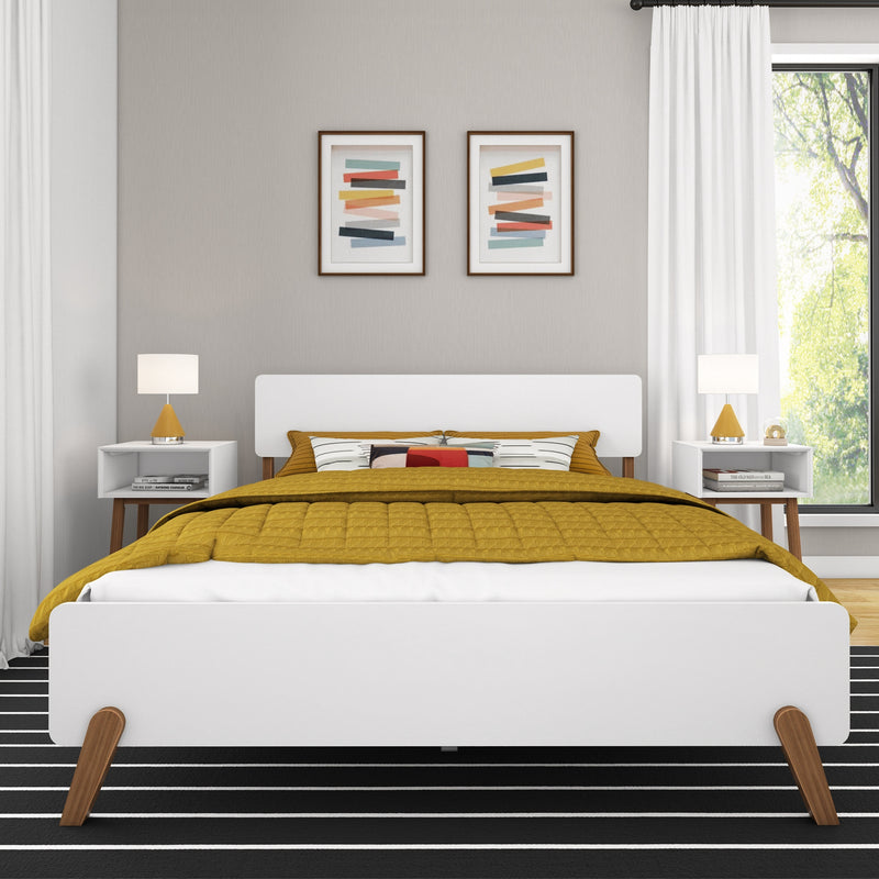 Contemporary modern bedroom with white mid-century bed frame, mustard yellow quilt and decorative pillows, matching white nightstands with gold table lamps, abstract framed wall art on a neutral gray wall, white curtains and sunlit window