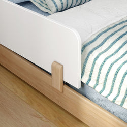 Close-up of a modern wooden bed frame with blue striped bedding.