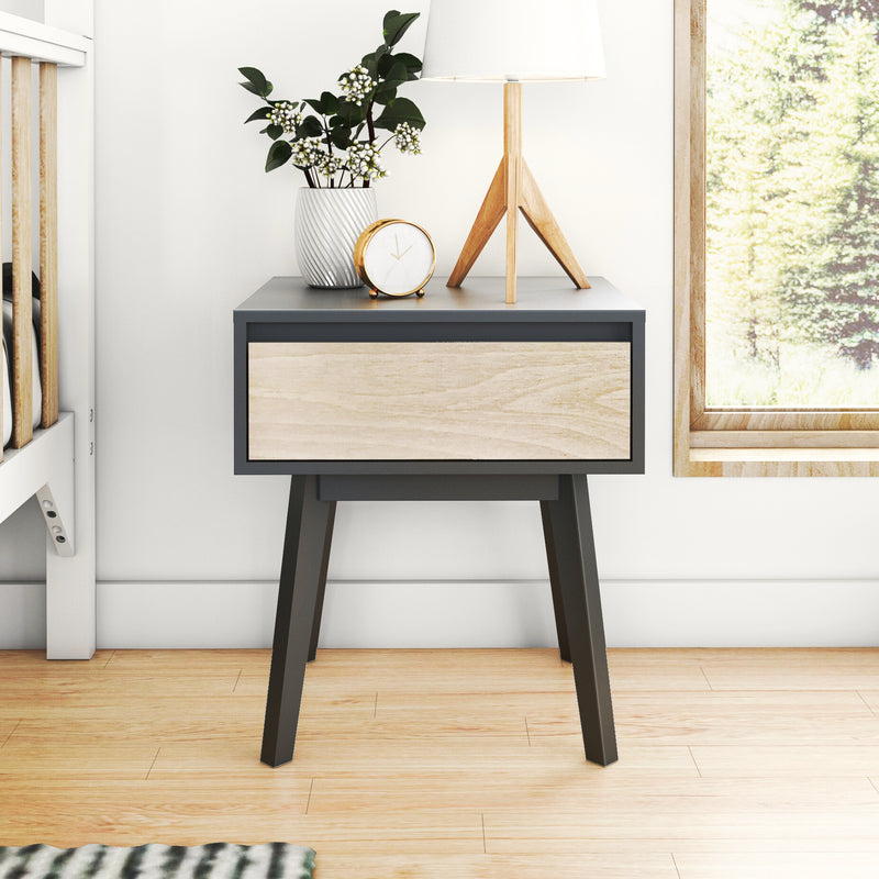 Modern Scandinavian two-tone wood and black nightstand with lamp, alarm clock, and potted plant in bright minimalist bedroom by window