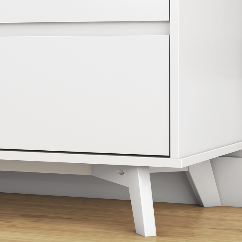 Close-up of white mid-century modern dresser corner with drawer detail and tapered wooden legs on hardwood floor