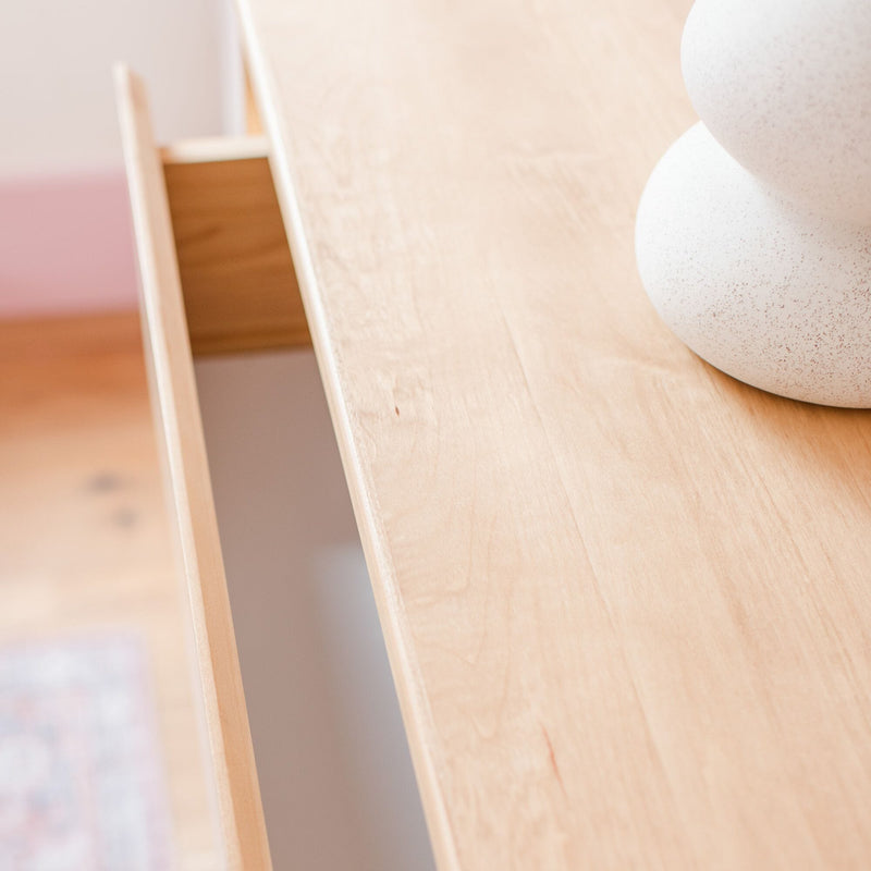 Light wood dresser top with partially open drawer and white speckled ceramic vase, minimalist Scandinavian bedroom decor close-up