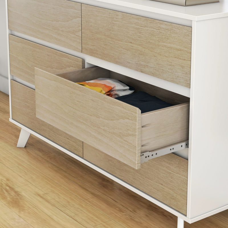 Modern mid-century dresser with light oak drawer fronts and white frame, open drawer revealing folded clothes on hardwood floor