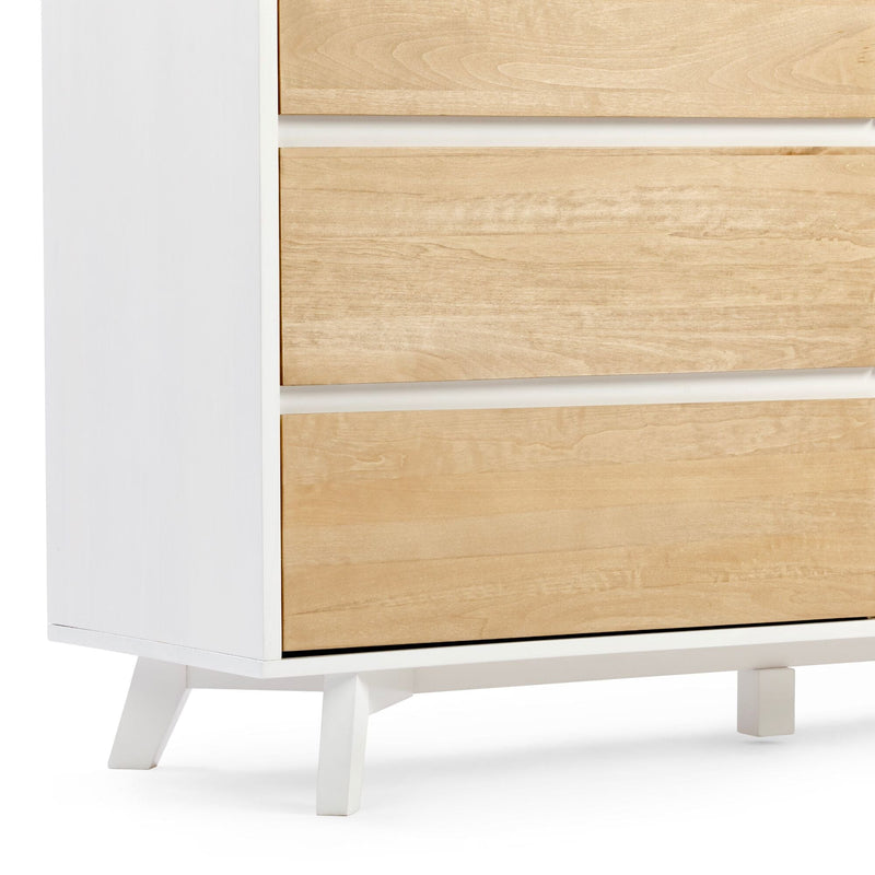 Close-up of a modern mid-century white nightstand with light wood drawer fronts, recessed horizontal gaps and angled tapered legs, minimalist bedroom furniture
