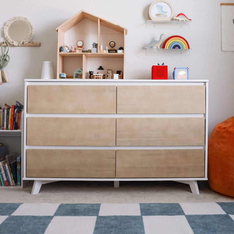 Modern nursery dresser with wooden dollhouse display, rainbow stacking toy and dinosaur figures on shelves, kids room storage and blue check rug