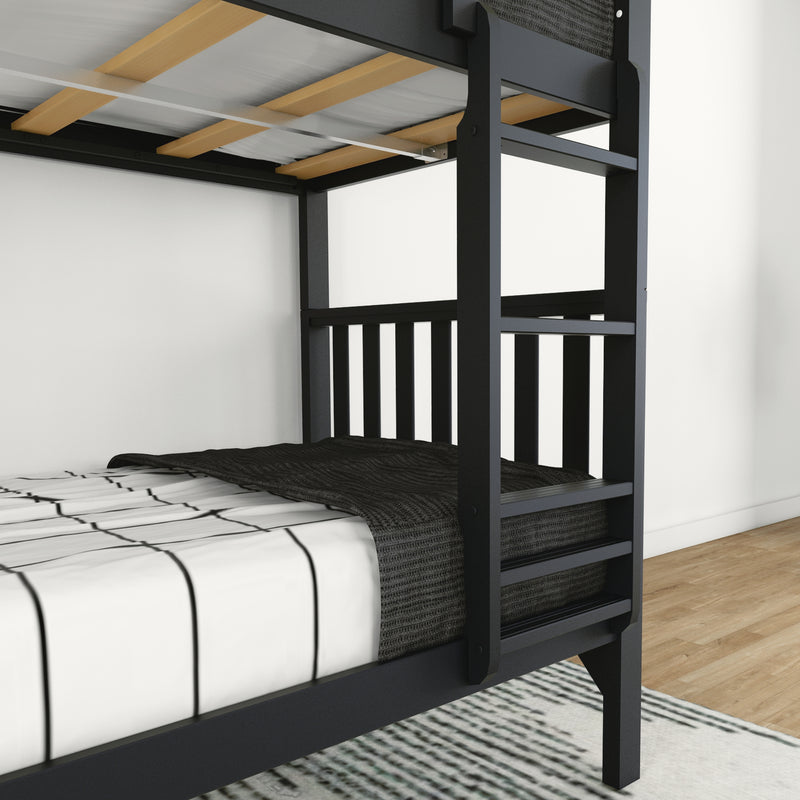 Close-up of black wooden twin-over-full bunk bed showing ladder, slatted mattress support, striped bedding and a knit blanket on hardwood floor