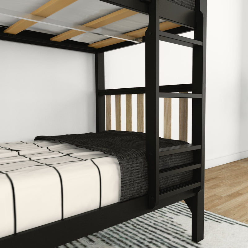 Close-up of a modern black metal bunk bed with wooden slats, striped white duvet and black knit blanket on a hardwood floor in a minimalist bedroom