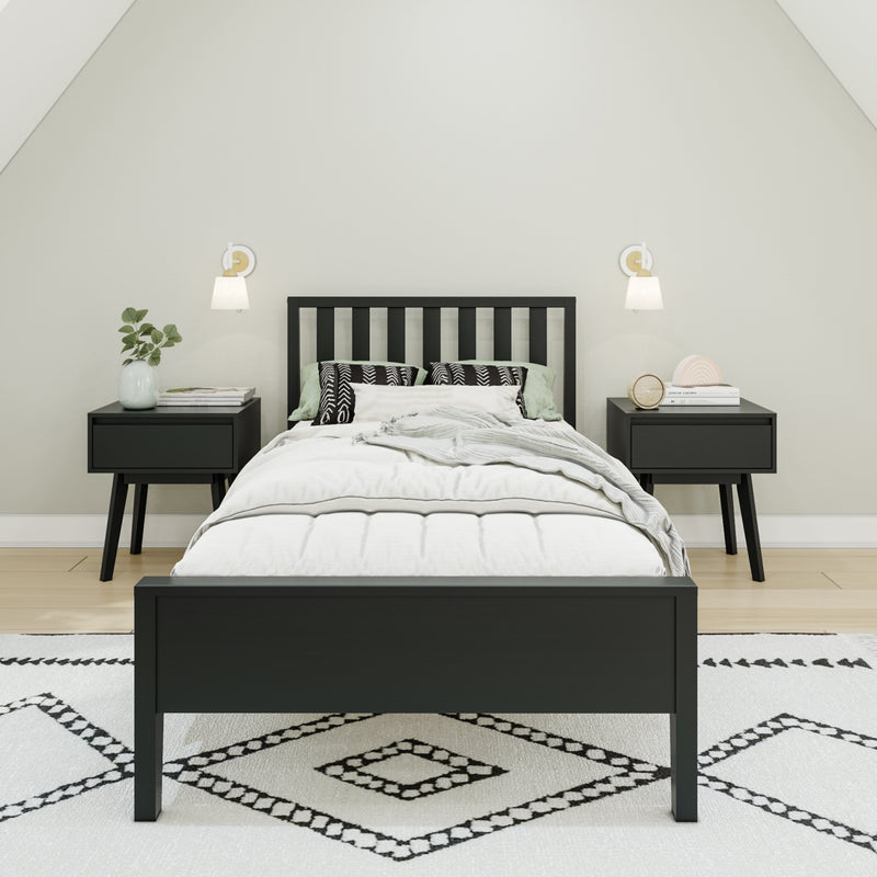 Minimalist Scandinavian bedroom with black wooden bed frame, white bedding, patterned rug, matching black nightstands and wall sconces.