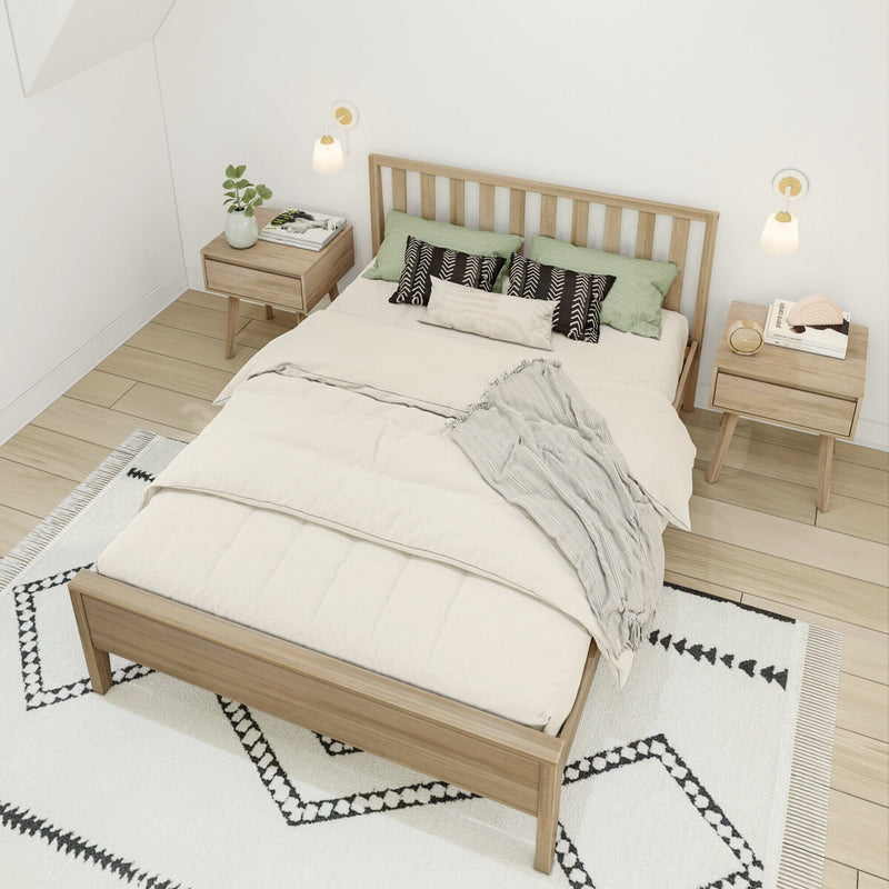 Minimalist Scandinavian bedroom with natural wood platform bed, neutral beige bedding, green and black patterned throw pillows, matching wood nightstands, modern wall sconces and geometric black-and-white area rug — modern cozy bedroom decor