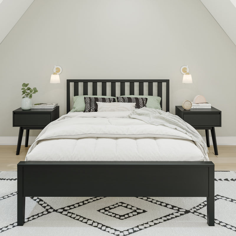Modern minimalist bedroom with black wooden bed frame, white bedding and pillows, matching black nightstands, wall sconces, potted plant and geometric area rug