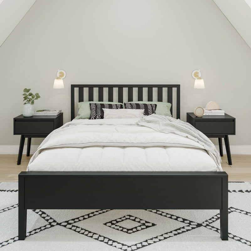 Modern minimalist bedroom with black wooden bed frame, white bedding and pillows, matching black nightstands, wall sconces, potted plant and geometric area rug