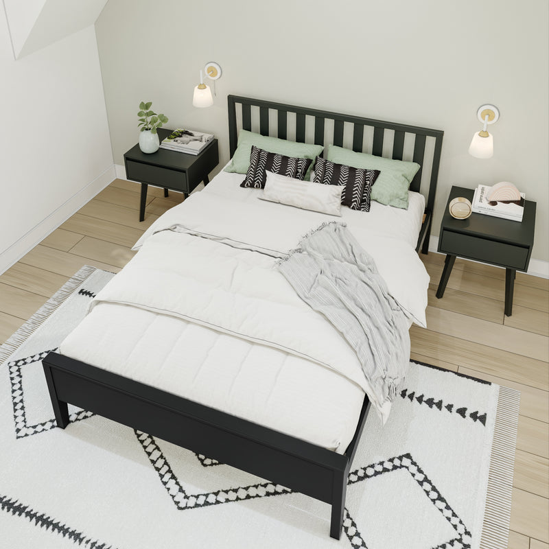 Minimalist modern bedroom with black slatted bed frame, white duvet, green pillows, black nightstands, wall sconces and patterned area rug